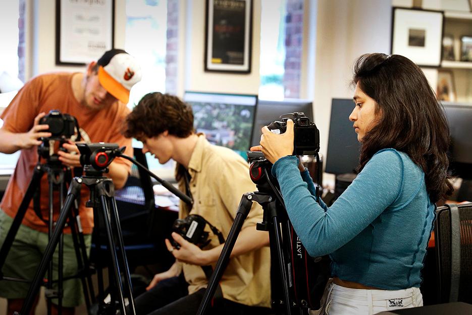 在2022年秋季的纪录片研究课程中，三名学生在DOCLab中使用相机设备工作.